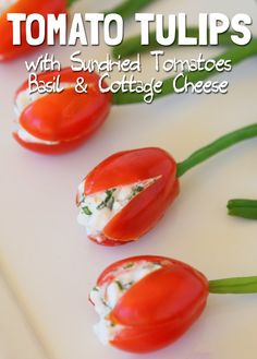 some tomatoes and cheese are arranged on a white surface with text overlay that reads tomato tulips with sundried tomatoes basil & cottage cheese