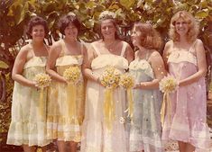 a group of women standing next to each other wearing dresses and holding bouquets in their hands