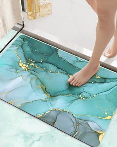 a person's feet on a blue and gold marble floor mat in a bathroom