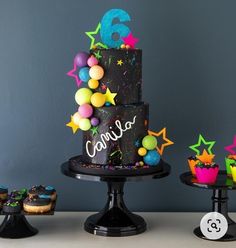 a birthday cake with stars and confetti on it, surrounded by cupcakes