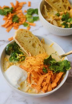 two bowls filled with soup and veggies on top of a marble countertop