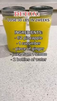 two jars filled with yellow liquid sitting on top of a counter