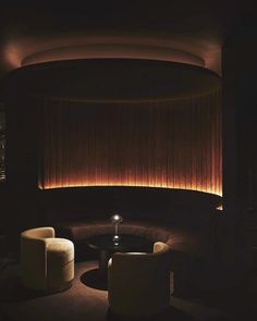 a dimly lit room with two chairs and a table in the center, along with a round coffee table