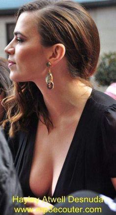 a woman with large breast standing in front of a group of people wearing gold earrings