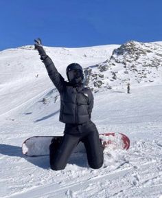 a snowboarder sitting on the ground with his arms in the air