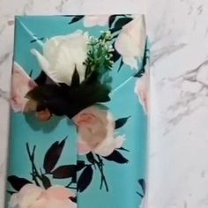 a blue box with flowers on it sitting on a marble counter top next to a white wall