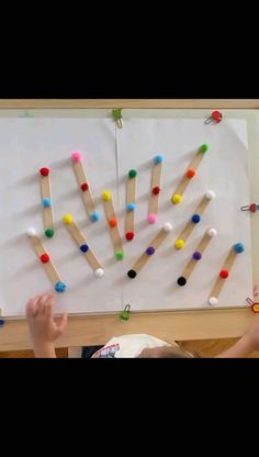 the child is playing with popsicles on the white board that he made out of matchesticks