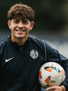 a smiling young man holding a soccer ball