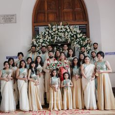 a group of people standing next to each other in front of a doorway with flowers