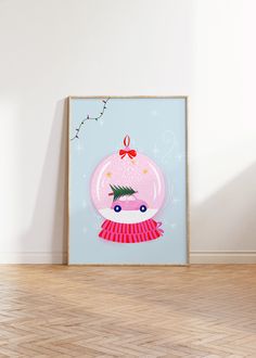 a pink christmas ornament with a red bow hanging on a wall next to a wooden floor