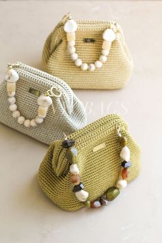 three purses with beads on them sitting next to each other in front of a white table