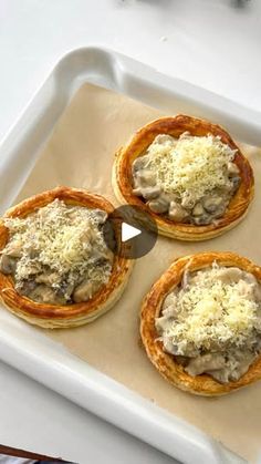 four mini pizzas on a baking sheet with cheese