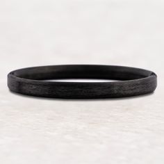 a close up of a black bracelet on a white surface with no one around it