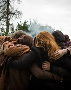 a group of people hugging each other outside