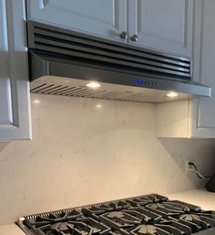 a stove top oven sitting inside of a kitchen next to white cabinets and counter tops