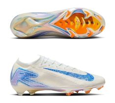 a pair of white and blue soccer shoes with orange accents on the soles, side by side