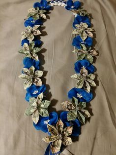 a blue and silver necklace with flowers on it's sides is laying on a bed