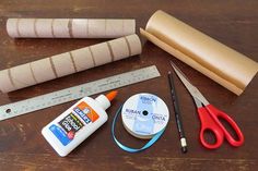 craft supplies laid out on a wooden table with ruler, tape, scissors and glue