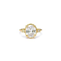 a yellow gold ring with an oval cut diamond in the center and three small diamonds on each side