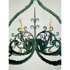 a green chandelier with two candles hanging from it's sides and an intricate design