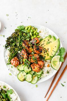 two plates filled with rice and vegetables next to chopsticks on a table top