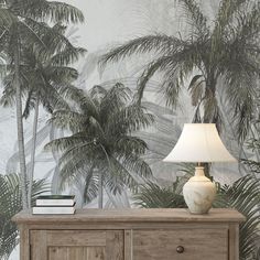 a white lamp sitting on top of a wooden dresser next to a palm tree wallpaper