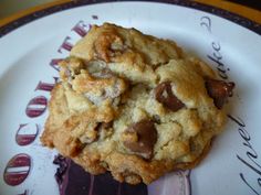 two chocolate chip cookies sitting on top of a white and brown plate with writing around it