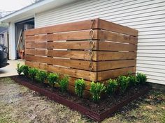 a large wooden box sitting on top of a garden bed in front of a house