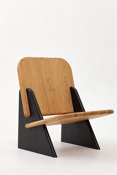 a wooden chair sitting on top of a white floor next to a black stand with a wooden stick sticking out of it