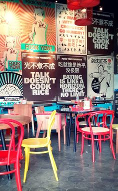 colorful chairs and tables in a restaurant with posters on the wall