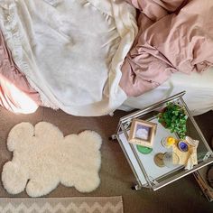 a bed with pink sheets, pillows and other items on the floor next to it