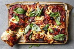 a square pizza with basil leaves on top