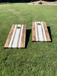 two wooden boards sitting on top of a grass covered field with holes in the middle