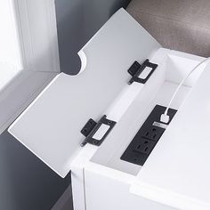 a white table with two black electrical outlets on it and a window in the background