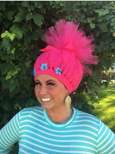 a woman with bright pink hair wearing a blue and white striped shirt smiles at the camera