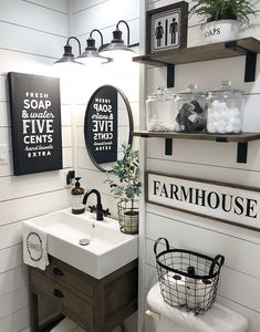 a white bathroom with black and white signs on the wall above the sink, along with two hanging shelves filled with toiletries