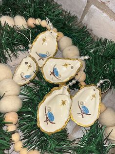 some ornaments are laying on the ground next to pine needles and balls with blue birds painted on them