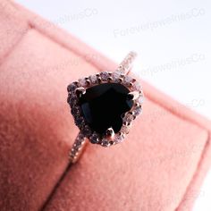 a black diamond ring sitting on top of a pink cushion