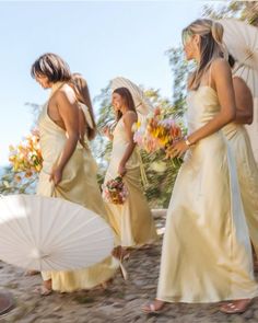 three bridesmaids in yellow dresses walking with umbrellas