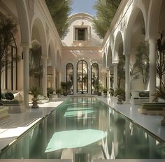 an indoor swimming pool surrounded by columns and arches, with trees in the background on either side