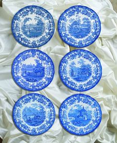 four blue and white plates sitting on top of a cloth covered table next to each other