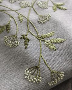 an embroidered piece of cloth with flowers and leaves on the side, sitting on top of a wooden table