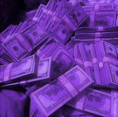 a pile of money sitting on top of a purple cloth covered bed in front of a window