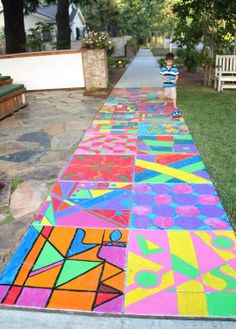 a child is walking down the sidewalk with colorful chalk art on it's side