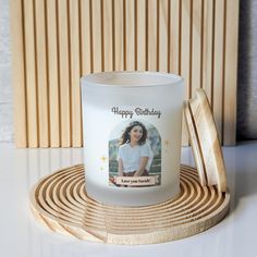 a white candle with a photo on it sitting on a wooden coaster next to a wall