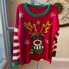 a red sweater with reindeer and snowflakes is hanging on a rack in front of a door