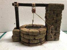 a small fire pit made out of rocks and rope on top of a white surface