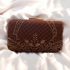 Elevate your ensemble with this exquisite handmade box clutch, a perfect fusion of traditional artistry and contemporary elegance. Crafted from luxurious raw silk, this clutch is adorned with intricate hand-embroidered zardozi and beadwork, showcasing the timeless beauty of this ancient technique. The detailed embroidery adds a touch of opulence, making it an ideal accessory for any special occasion. The clutch features a premium metal frame and a sleek rectangular knob, ensuring both durability Luxury Handmade Antique Bags, Elegant Clutch For Festivals And Receptions, Elegant Handmade Brown Clutch, Elegant Clutch For Receptions And Festivals, Elegant Evening Bag For Receptions And Festivals, Elegant Clutch For Reception And Festivals, Hand Embellished Rectangular Clutch For Reception, Luxury Reception Clutch With Intricate Embroidery, Elegant Evening Bag For Receptions And Festive Occasions