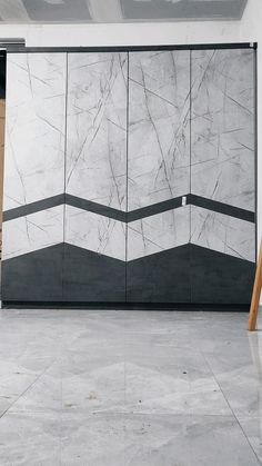 a large white marble wall with black and grey lines on the side, next to a wooden door