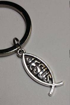 a metal keychain with the word jesus on it and a fish charm attached to it